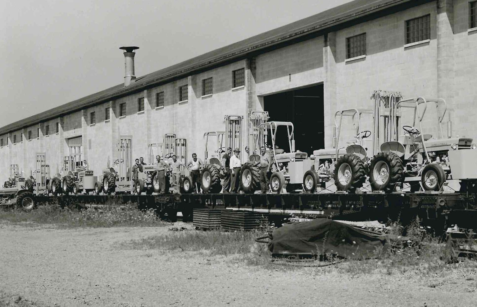 Historic black-and-white photo of Harlo equipment being loaded for shipment outside the factory